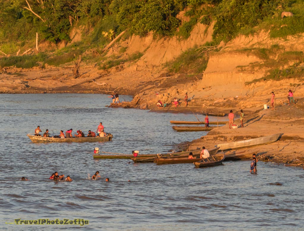 Ludzie na brzegu rzeki Amazonki, zdjęcie zrobione z dziobu wielkiej łodzi